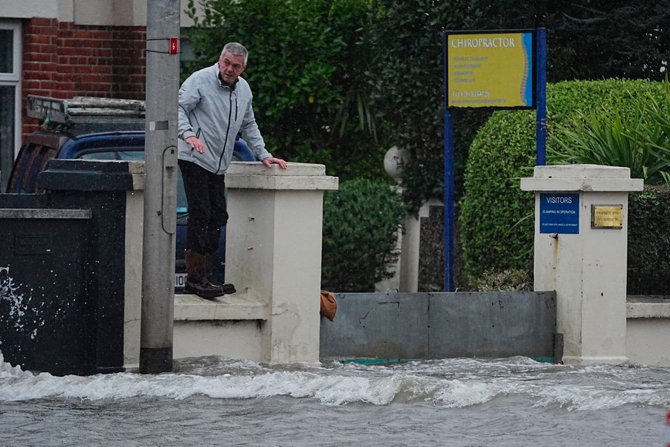 A man tries to keep his feet dry after flooding on Clontarf Road in Dublin. Photo: PA